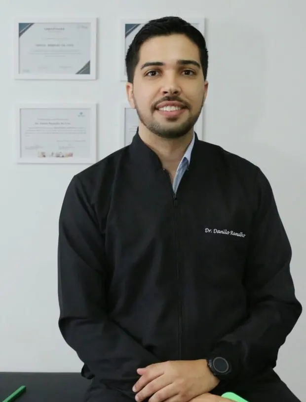 Retrato do Dr. Danilo Ramalho de jaleco preto na clínica